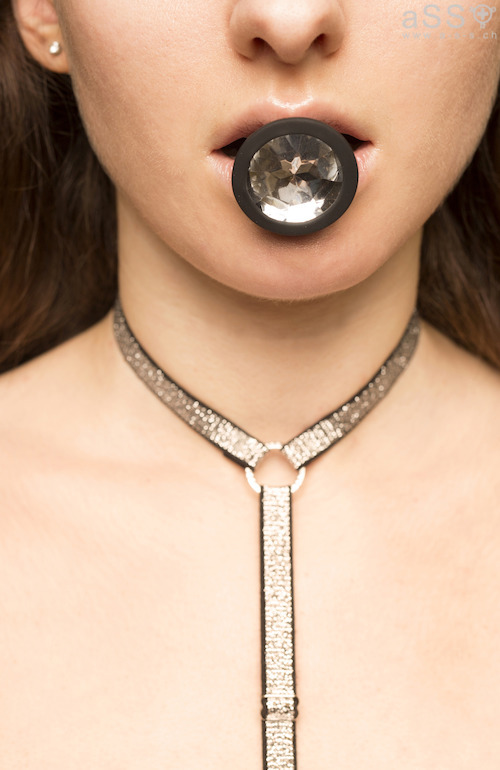 Lencería hecha a mano con tirantes de metal. La lencería es de una sola pieza y llega hasta el cuello. En la parte inferior, la lencería se sujeta con un plug anal. 