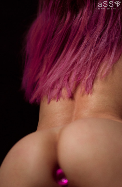 Lencería hecha a mano con tirantes elásticos de color metálico. La lencería es de una sola pieza y llega hasta el cuello. La parte delantera del cuello tiene un pequeño corazón de metal grabado con la inscripción «Love your aSS». En la parte inferior, la lencería se sujeta con un plug anal. Todas las correas son ajustables.