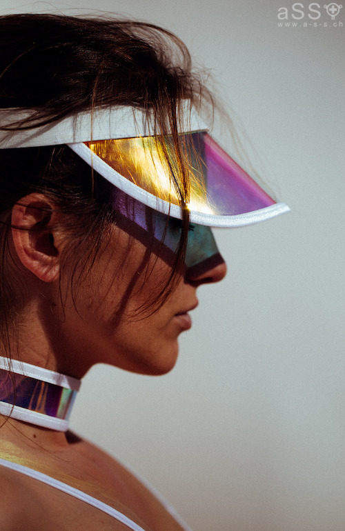Sehr aussergewöhnliches Lingerieset in einer Kombination von Elastikbändern mit irrisierendem, durchsichtigem Vinyl. Das Top ist Balkonartig und die Brustwarzen sind nicht bedeckt. Auch beim Höschen wird der Intimbereich nicht verdeckt. Vom Höschen aus gehen Elastikbänder runter zu den Oberschenkeln, wo jeweils ein Strapsband befestigt ist. Zum Set gehören auch ein Halsband sowie einen "Visor" (Sonnenschutz".  