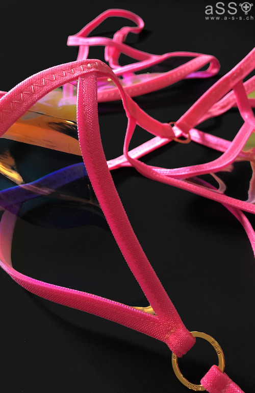 Sehr aussergewöhnliches Lingerieset in einer Kombination von Elastikbändern mit irrisierendem, durchsichtigem Vinyl. Das Top ist Balkonartig und die Brustwarzen sind nicht bedeckt. Auch beim Höschen wird der Intimbereich nicht verdeckt. Vom Höschen aus gehen Elastikbänder runter zu den Oberschenkeln, wo jeweils ein Strapsband befestigt ist. Zum Set gehören auch ein Halsband sowie einen "Visor" (Sonnenschutz".  